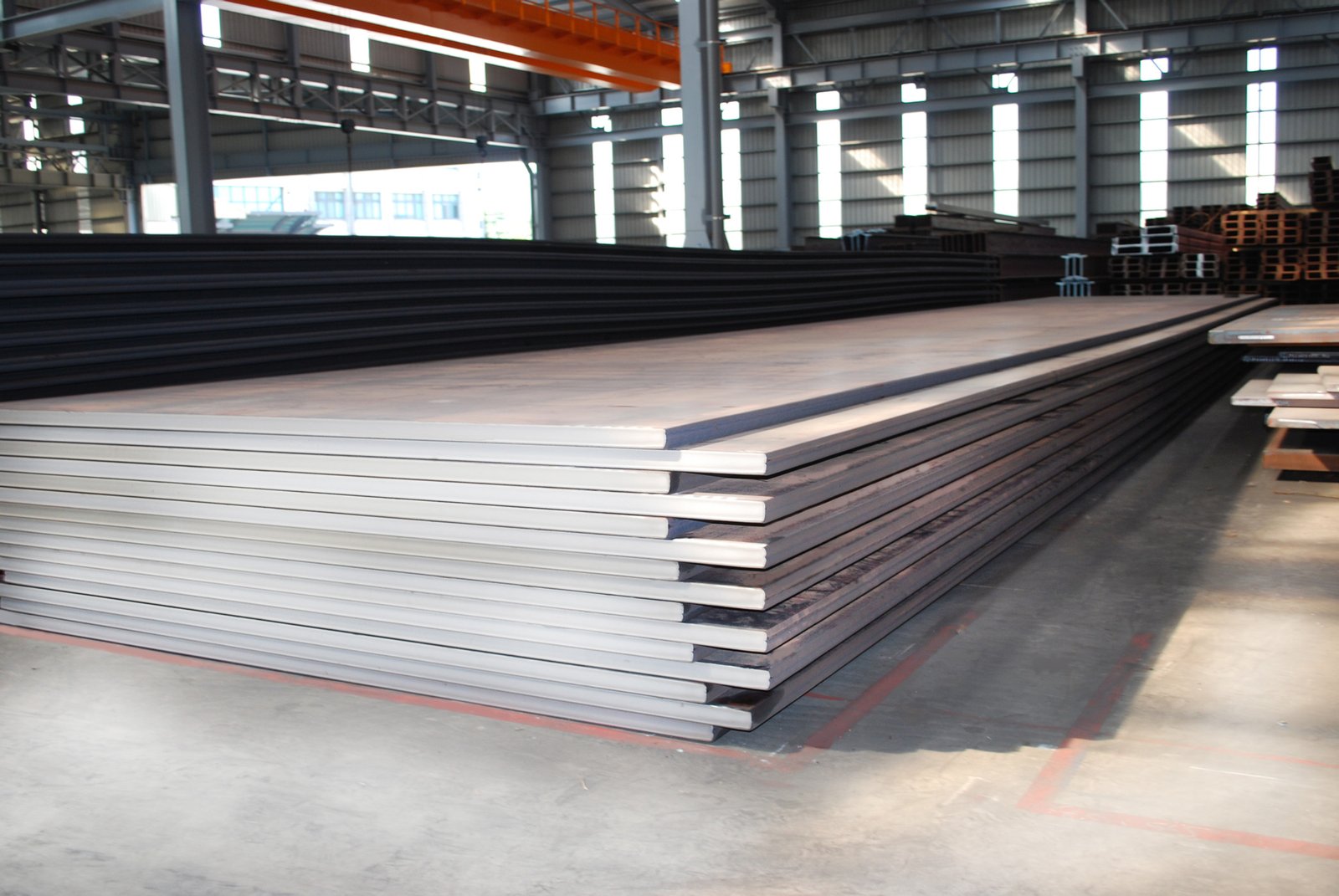 Stack of API 2H Gr.42 offshore marine grade steel plates in a warehouse