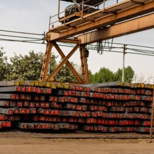 Stacked AISI 1045 steel bars in an outdoor storage yard with an overhead crane